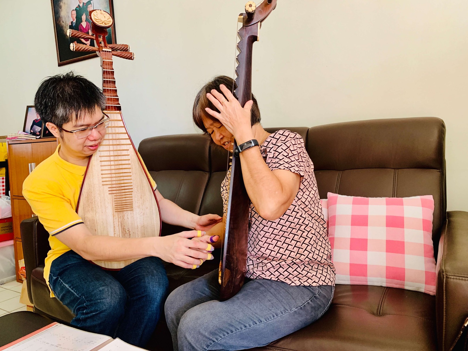 Senior learner being taught pipa hand position by teacher Nicholas Ng at home